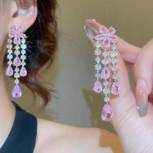 Close-up of pink flower earrings with long sparkling tassel drops and zircon stones