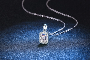 Macro shot of emerald cut moissanite pendant with halo setting on a silver chain