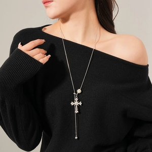 Detailed view of long silver cross necklace with tiger eye stone and tassel on a model