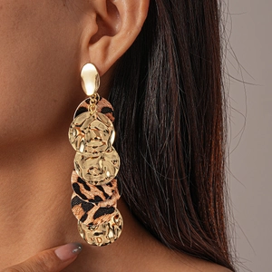 Close-up of leopard print dangle earrings on model featuring gold textured metal discs