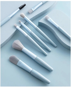 Detail of 8 light blue professional makeup brushes with soft white bristles and metal handles