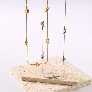 Detailed view of 18K gold and silver snake chains with asymmetric knot details on stone