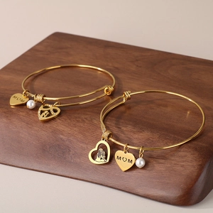 Detail of gold MOM heart pendant bracelet with silhouette charms and small pearls