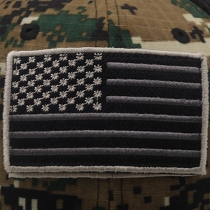 Detail of American flag tactical patch and digital camouflage pattern on cotton baseball cap