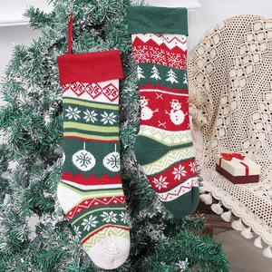 Knitted Christmas stockings with snowman and tree patterns hanging on a decorated tree