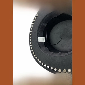 Detalle del forro interior de un sombrero negro con etiqueta de talla 57 y perlas