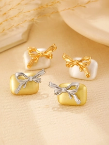 Detailopname van elegante strik oorbellen in parelwit en mat gouden afwerking