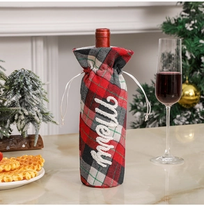 Détail d'un couvre-bouteille à carreaux rouges avec broderie Merry sur table festive