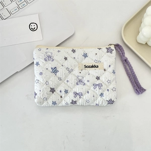 Close-up of quilted floral cosmetic bag with bear pattern and woven purple wristlet
