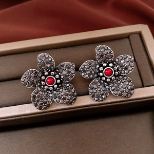 Detailed close-up of vintage floral earrings with black crystals and red center bead