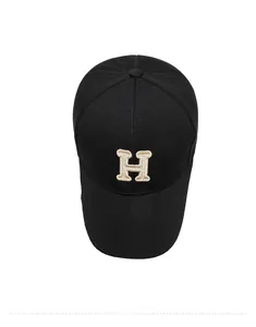 Top view of a black baseball cap with embroidered beige letter H in breathable fabric
