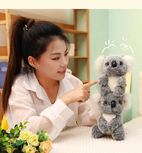 Close-up of cute mother and baby koala plush toy with soft grey fur held by a person