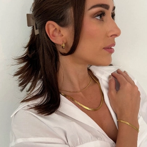 Golden flat snake bone chain necklace set with matching earrings and bracelet on model