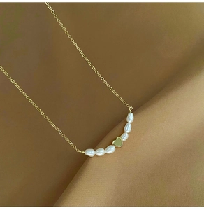 Close-up of gold heart pendant and freshwater pearls on elegant champagne silk fabric