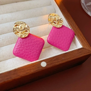 Detail of rose pink litchi grain leather square drops on golden irregular metal earrings