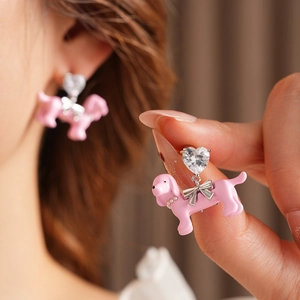 Detailed close-up of pink dachshund earrings with heart crystals and silver bows