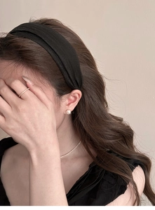 Detail shot of wide black silk headband with pearls and elegant accessories on model