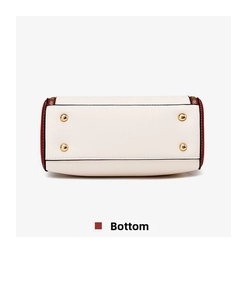 Detailed bottom view of the two-tone handbag showing four protective gold metal studs