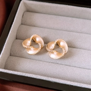 Macro shot of 14K gold plated spiral earrings with pavé diamond detail in a jewelry box