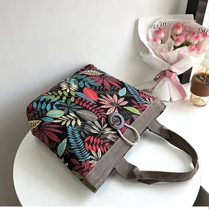 Detail of canvas tote bag featuring ethnic leaf print and decorative wooden button closure