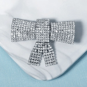 Elegante pinza para el pelo con lazo plateado y diamantes sobre mármol y azul