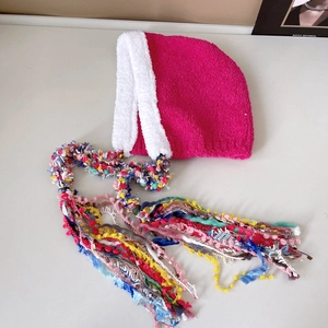 Close-up of vibrant pink knitted hat featuring long colorful tassels and soft white fur trim