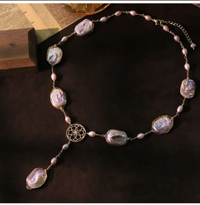 Detail of baroque pearl necklace with golden floral motif on vintage brown velvet background
