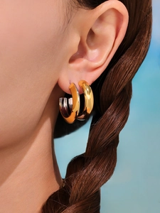 Detailed view of polished two-tone gold and silver C-shaped chunky hoop earrings on model