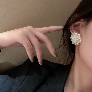 Close-up of elegant white pearl floral earrings worn on ear for stylish fashion look