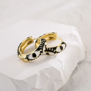 Bohemian gold-plated earrings with black and white evil eye charms on a white stone base