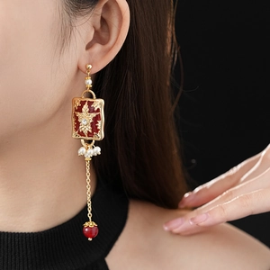 Detail of vintage gold tassel earrings with red enamel and pearls worn by a model