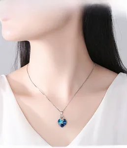 Close-up of heart-shaped blue crystal pendant necklace worn on neck for elegant look
