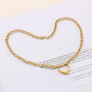 Dettaglio di un ciondolo a cuore in oro lucido su catena a maglie con chiusura a moschettone