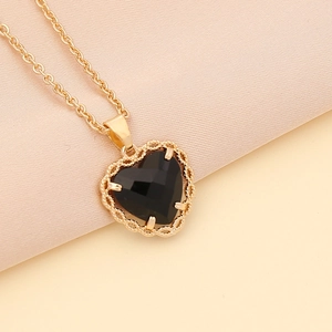 Detailed close-up of a faceted black heart pendant set in an elegant golden lace frame
