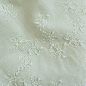 Close-up of light green mesh tote bag with white floral embroidery and fine texture