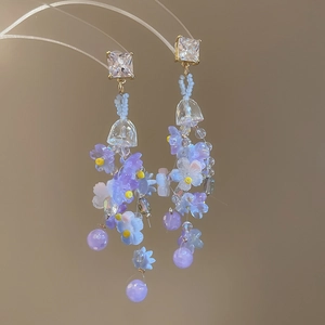 Close-up of floral crystal tassel earrings with purple beads and shiny clear crystals