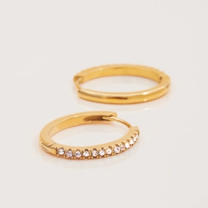 Macro detail of gold-plated huggie hoop earrings with sparkling crystal pavé inlay