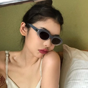 Retro oval sunglasses with gray translucent frames and gold accents on a female model