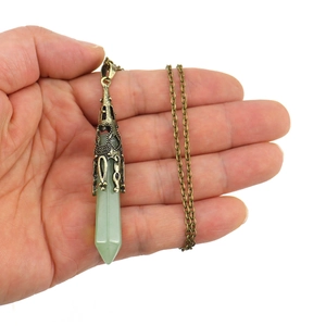 Green crystal hexagonal pendant necklace with antique bronze filigree cap held by hand