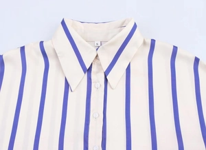 Dettaglio ravvicinato del colletto beige a righe verticali blu con etichetta taglia S