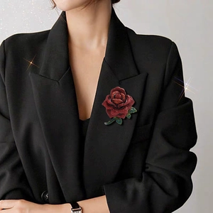 Vintage rose brooch with red rhinestones and green gems on a black suit jacket
