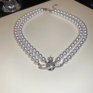 Macro detail of a double-row pearl necklace with a silver rhinestone-studded orb pendant
