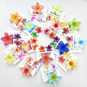 Set of colorful gradient plumeria flower hair claws for vacation styling on white backdrop