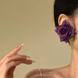 Detailed view of handmade purple fabric rose earrings with realistic water droplets