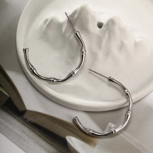 Detailed close-up of silver bamboo-style hoop earrings on a decorative stone tray