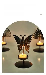 Detail of a black metal butterfly candle holder with warm tea light and elegant shadows