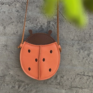 Detail view of ladybug-shaped kids leather bag with litchi texture and orange finish