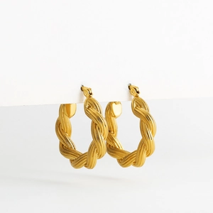 Macro shot of gold-plated twisted rope texture hollow earrings on a white stand