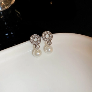 Close-up of silver stud earrings with sparkling rhinestones and white teardrop pearls