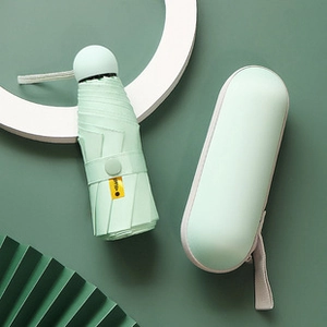 Mini mint green UV umbrella folded with matching capsule hard case on dark green background